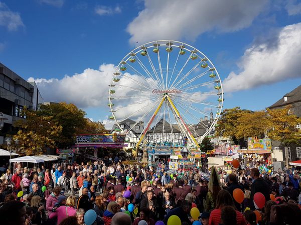 Kirmes Marktplatz mit Besuchern und Riesenrad im Hintergrund