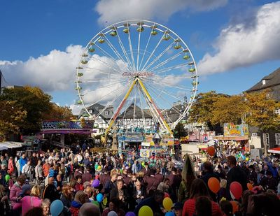 Kirmes Marktplatz mit Besuchern und Riesenrad im Hintergrund